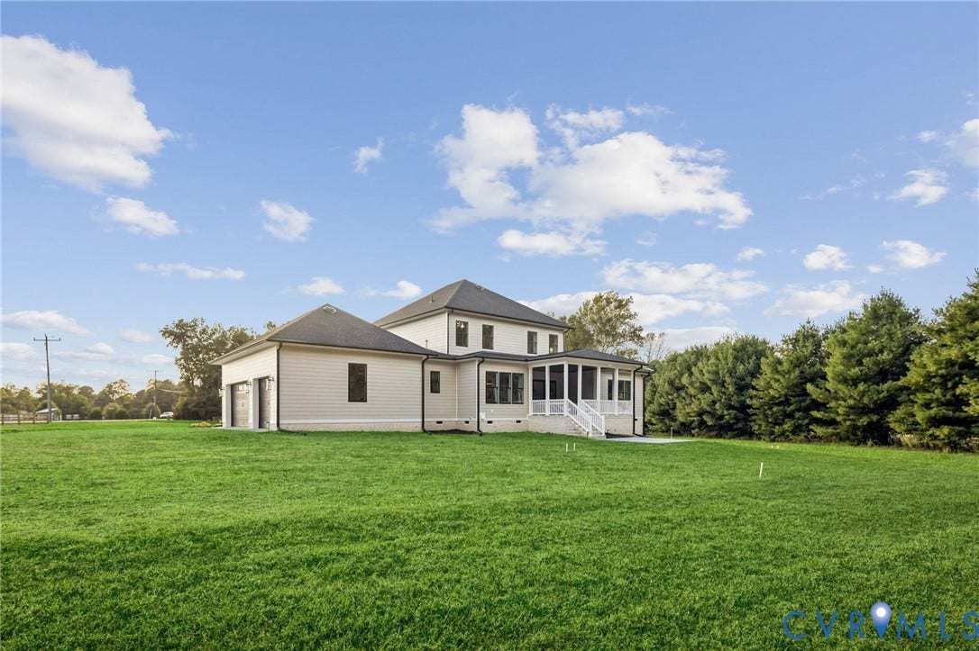 9275 Topeka Road, Quinton, VA 23141 Expansive green lawn surrounds a modern residence featuring a screened-in porch, attached garage, and mature tree line