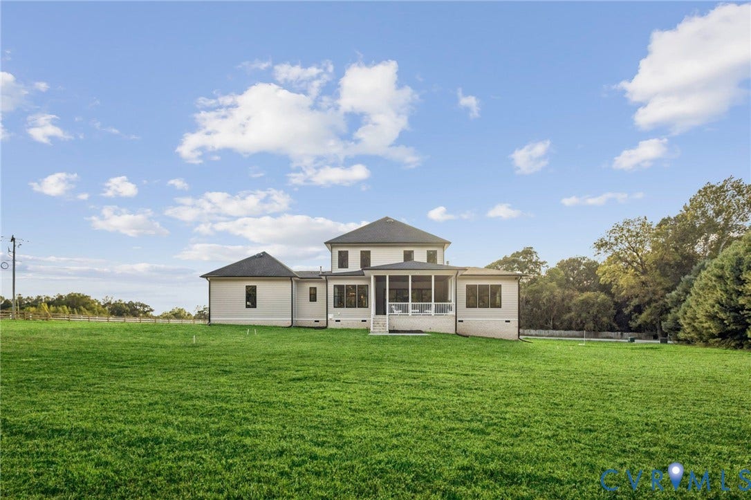 9275 Topeka Road, Quinton, VA 23141 Expansive green lawn surrounds a contemporary home featuring light-colored siding, a screened porch, and a multi-level roofline