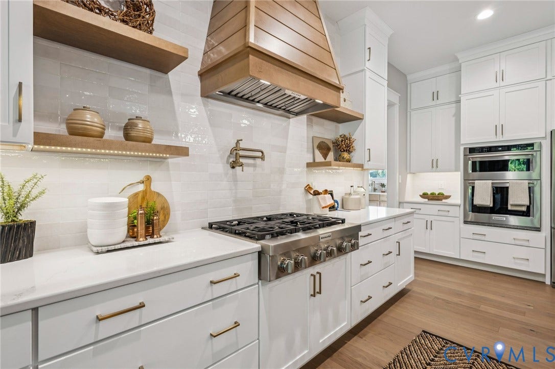 9275 Topeka Road, Quinton, VA 23141 Contemporary kitchen featuring a wood-finish range hood, stainless steel gas range, double wall ovens, and white shaker cabinetry with brass hardware