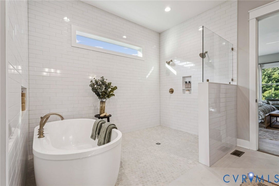 9275 Topeka Road, Quinton, VA 23141 Freestanding soaking tub with a floor-mounted faucet, complemented by a walk-in shower featuring a glass panel, dual shower heads, and built-in niches