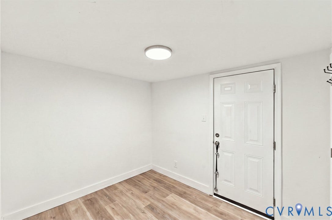 20 Victor Street, Geo Moss Estate, Hampton, VA 23669 Room featuring neutral walls, wood-finish flooring, and a six-panel door with metallic hardware, illuminated by a flush-mount circular ceiling light