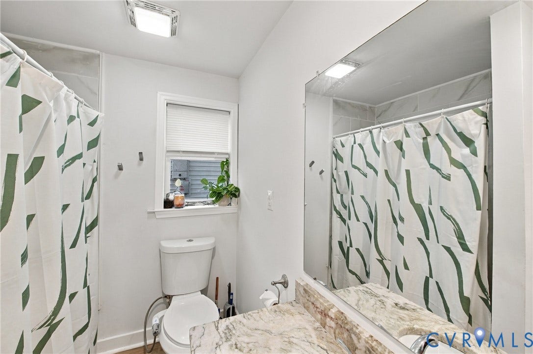 20 Victor Street, Geo Moss Estate, Hampton, VA 23669 Full-width vanity mirror, stone-finish countertop with an integrated sink, polished chrome faucet, tub-and-shower combination featuring a stone-finish tile surround, and an operable window