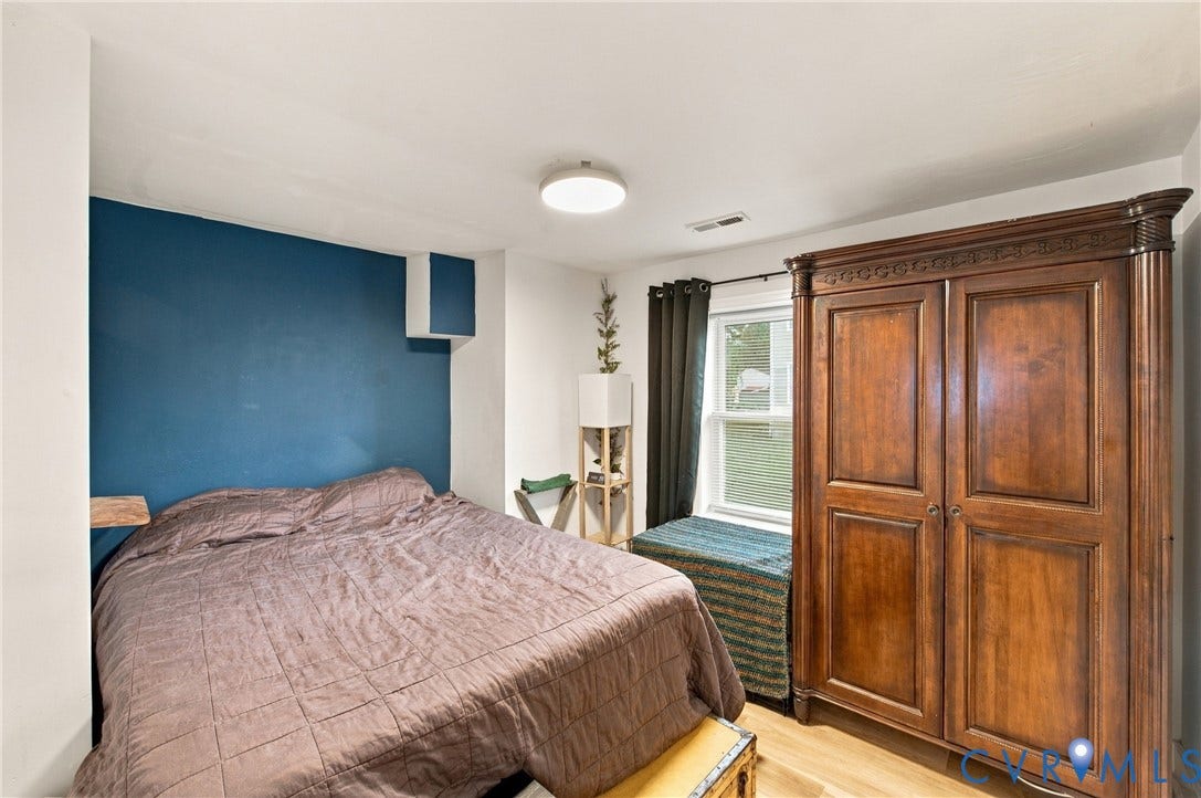 20 Victor Street, Geo Moss Estate, Hampton, VA 23669 Room featuring a bold blue accent wall, neutral wall coloring, wood-finish flooring, and a window with casing