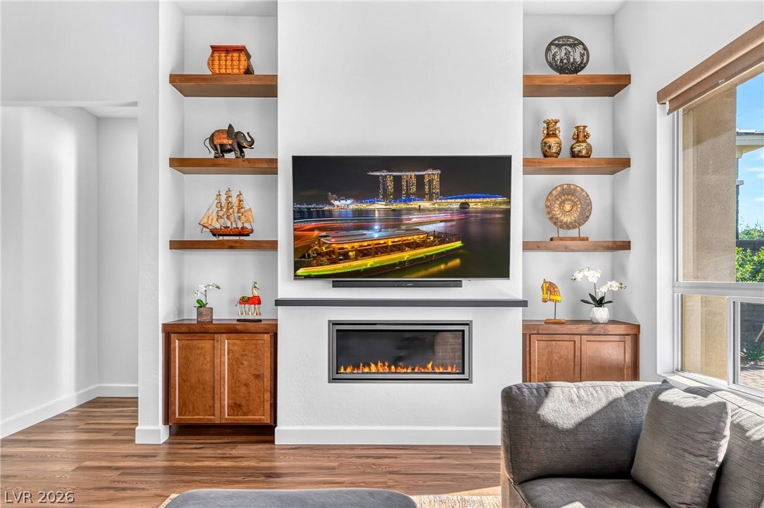 29 Porto Malaga Street, Henderson, NV 89011 A striking fireplace forms a focal point, flanked by custom cabinetry and open shelving, adding both warmth and style.