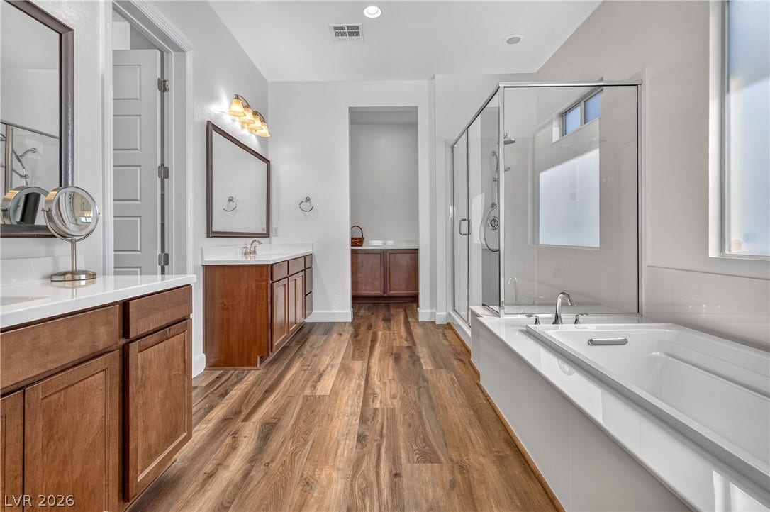 29 Porto Malaga Street, Henderson, NV 89011 Luxurious primary bathroom featuring a large soaking tub, spacious glass shower, and rich wood-toned vanities.
