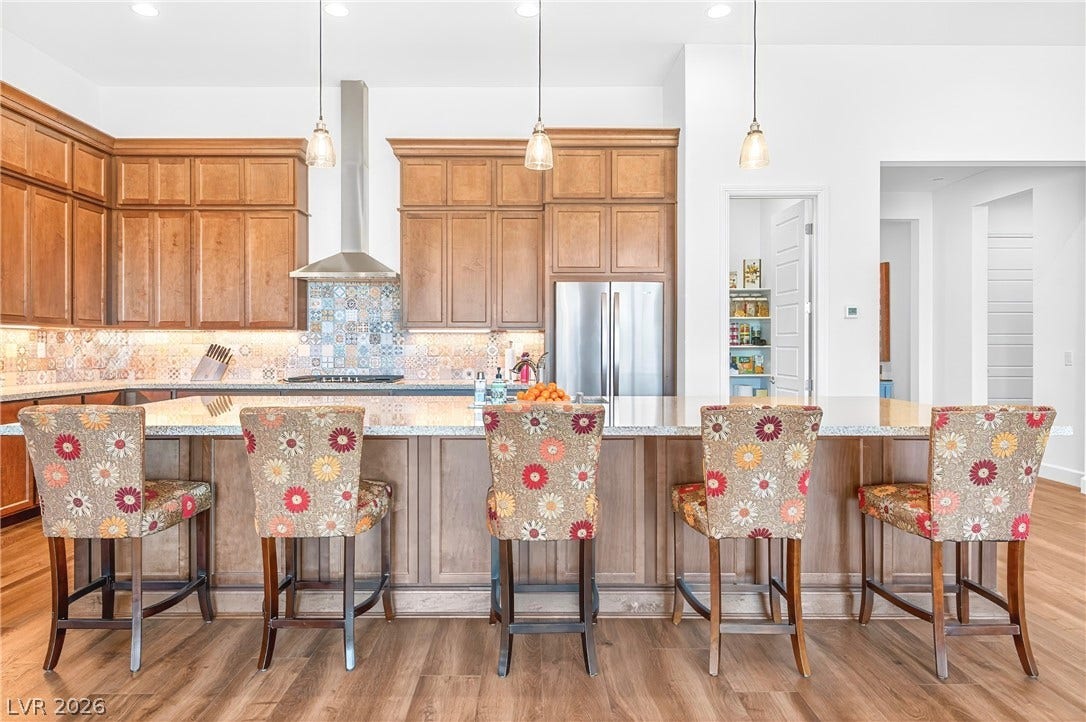 29 Porto Malaga Street, Henderson, NV 89011 A gourmet kitchen offers rich wood cabinetry, a striking backsplash, and a functional island with seating.