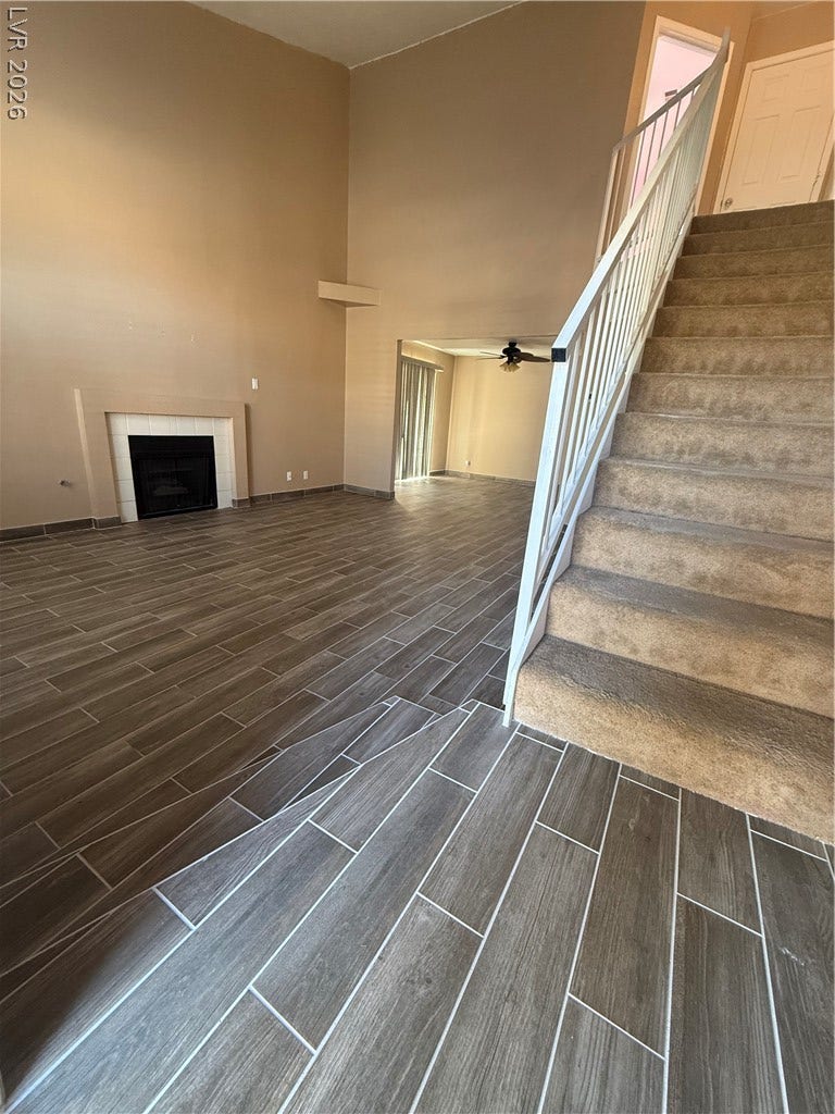 2823 Shannon Cove Drive, Henderson, NV 89074 High ceilings and modern wood-look tile floors frame a cozy fireplace under carpeted stairs.