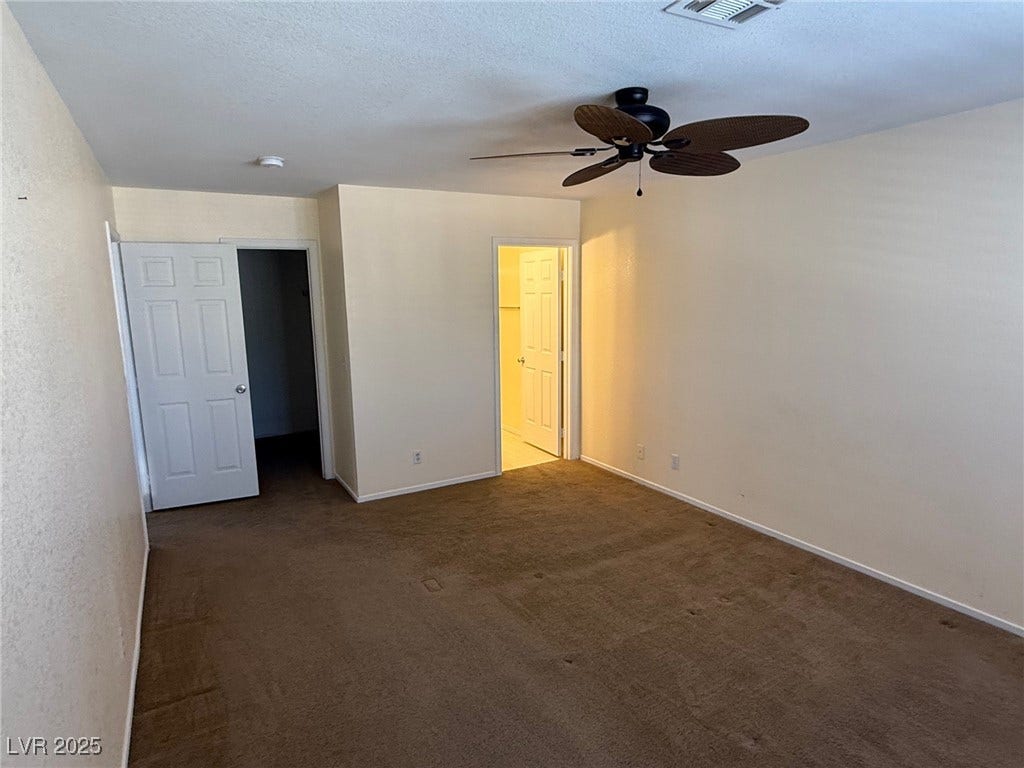 2823 Shannon Cove Drive, Henderson, NV 89074 Unfurnished bedroom featuring dark colored carpet, a ceiling fan, a textured ceiling, and a walk in closet