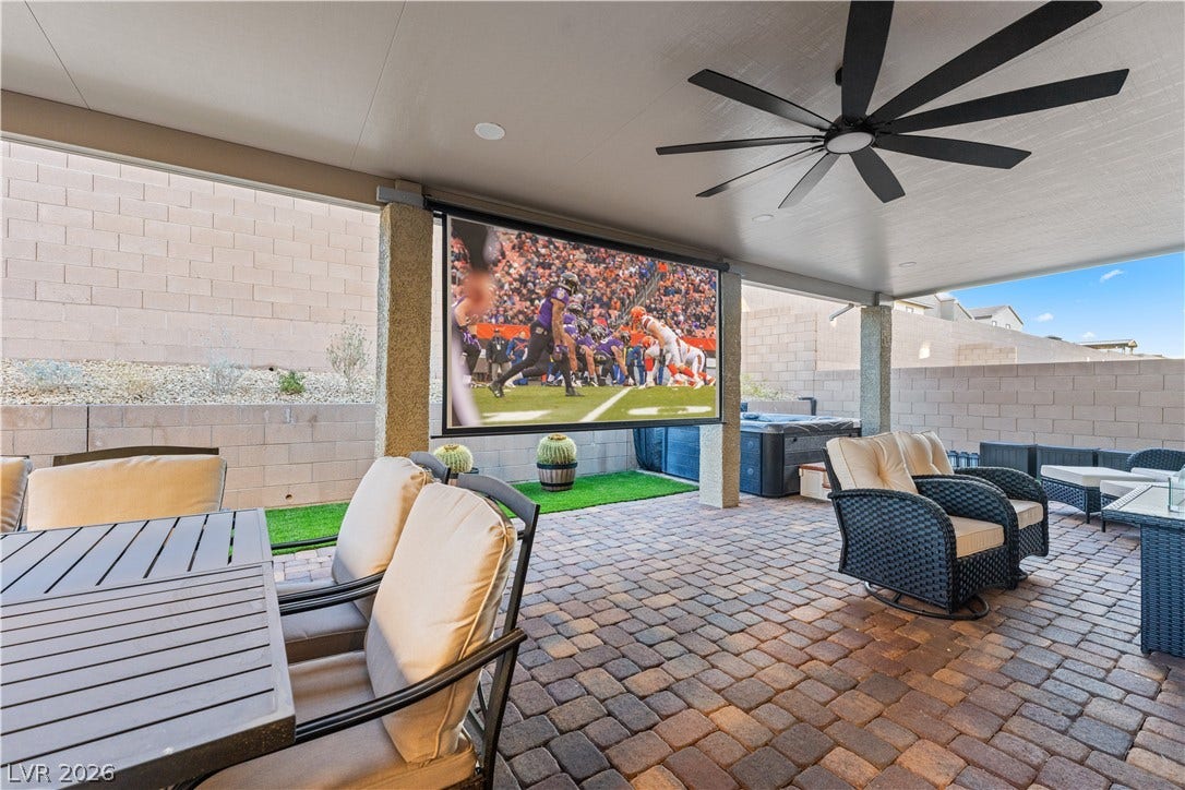 145 Rohan Crest Avenue, Henderson, NV 89011 Entertainers backyard w/ extended covered patio, dining and seating areas, spa, and retractable screen w/ projector for outdoor living and movie nights.