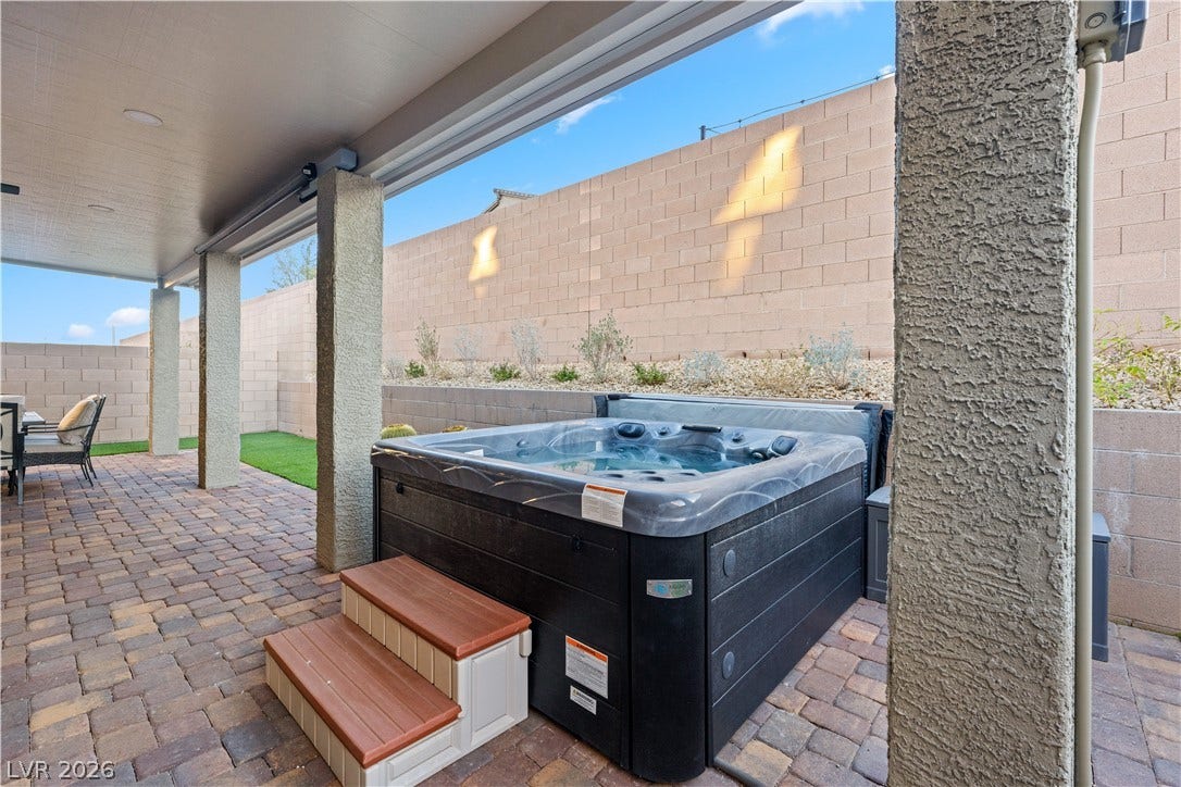 145 Rohan Crest Avenue, Henderson, NV 89011 Entertainers backyard w/ extended covered patio, dining and seating areas, spa, and retractable screen w/ projector for outdoor living and movie nights.