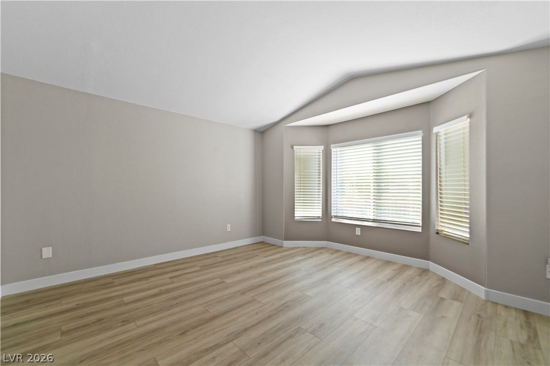 2154 High Mesa Drive, Henderson, NV 89012 A well-lit room showcasing rich hardwood flooring and bright bay windows with elegant blinds.
