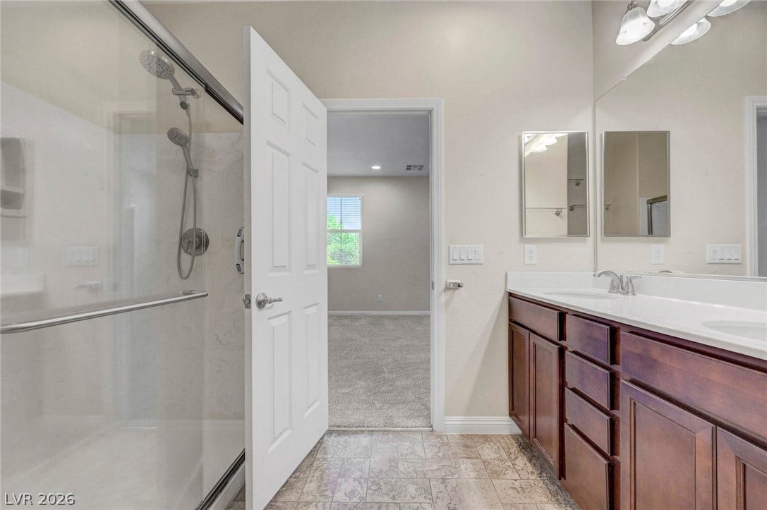 3086 Ripe Peak Lane, Henderson, NV 89044 This bathroom features a double vanity and a spacious walk-in shower with modern fixtures.