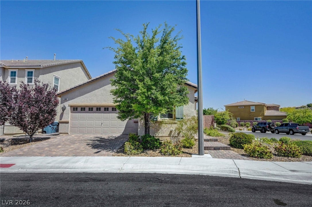 3086 Ripe Peak Lane, Henderson, NV 89044 This residence features a convenient attached garage and a well-maintained brick paver driveway.