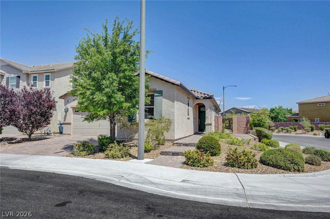 3086 Ripe Peak Lane, Henderson, NV 89044 This inviting residence features a paver driveway, lush landscaping, and a welcoming arched entry.