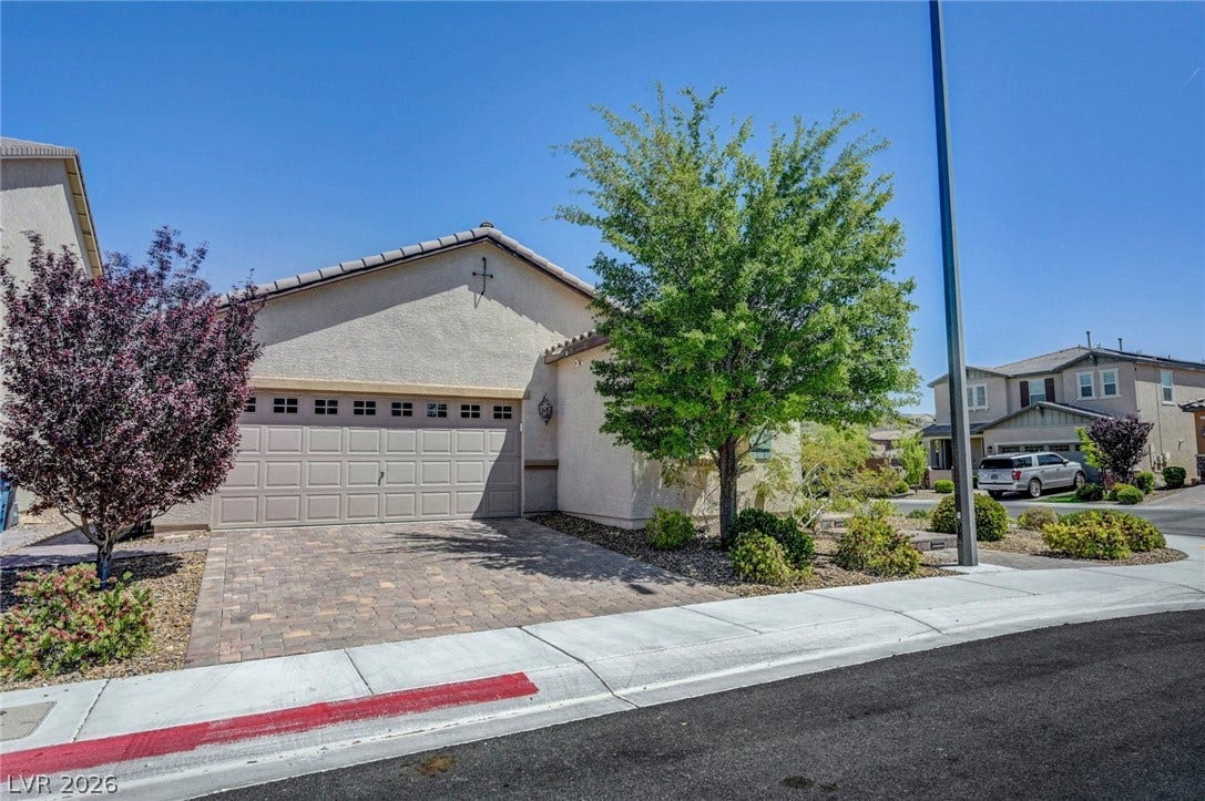 3086 Ripe Peak Lane, Henderson, NV 89044 A well-maintained suburban home featuring a paved driveway, lush landscaping, and an attached garage.