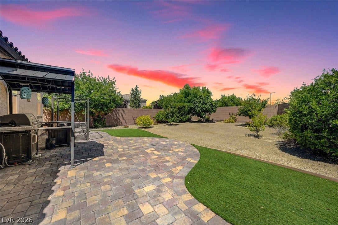 3086 Ripe Peak Lane, Henderson, NV 89044 This spacious backyard features a paved patio, perfect for outdoor living under a vibrant sky.