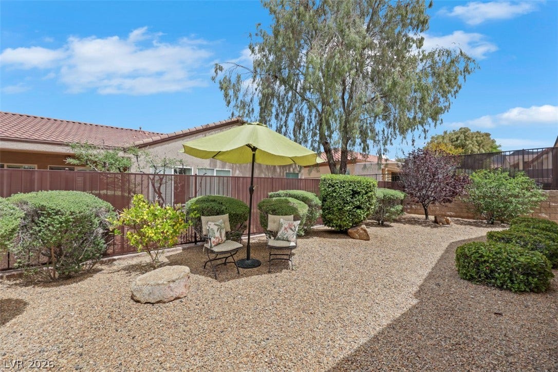 2408 Black River Falls Drive, Henderson, NV 89044 This tranquil outdoor space offers a peaceful retreat with lush greenery and a comfortable seating area.