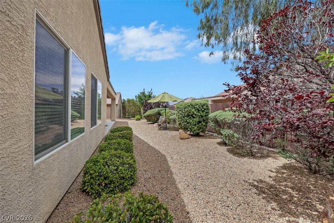2408 Black River Falls Drive, Henderson, NV 89044 This tranquil yard features gravel landscaping, lush bushes, and a protective fence.