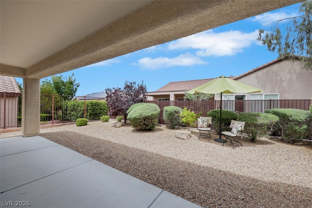 2408 Black River Falls Drive, Henderson, NV 89044 This tranquil outdoor space features a covered patio area and meticulously landscaped yard, perfect for relaxation.