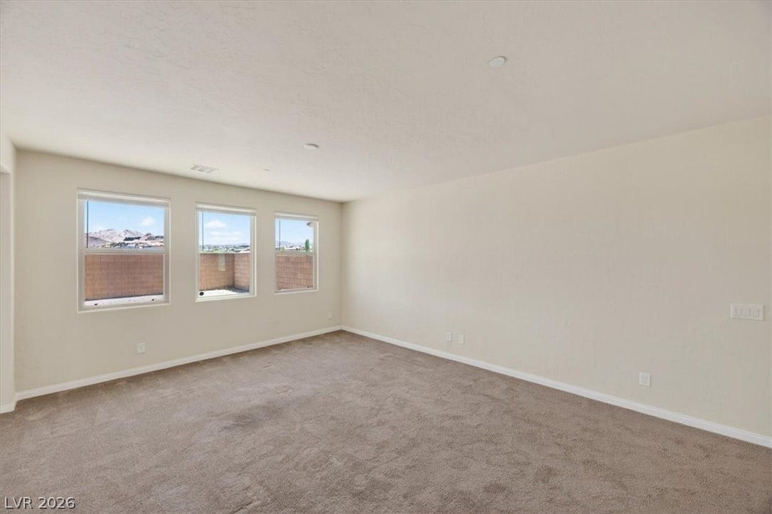 1116 Strada Cristallo, Henderson, NV 89011 A spacious room offers comfortable carpet flooring and multiple windows framing mountain vistas.