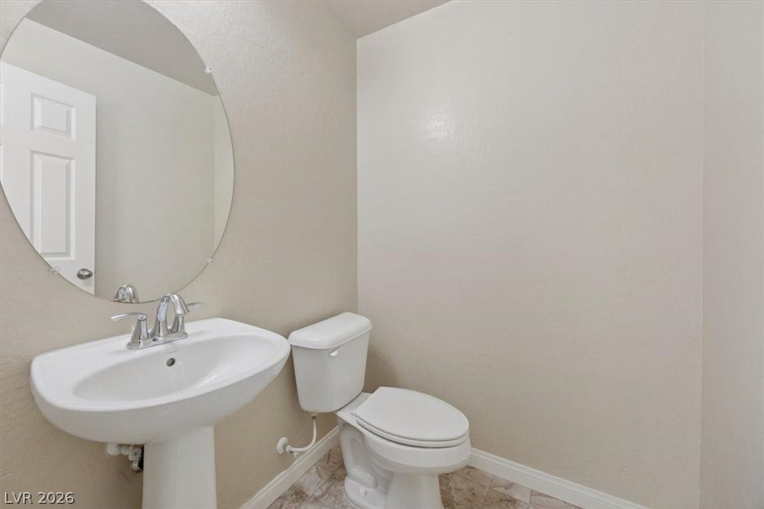 1116 Strada Cristallo, Henderson, NV 89011 A compact and functional bathroom features a modern pedestal sink and mirror.