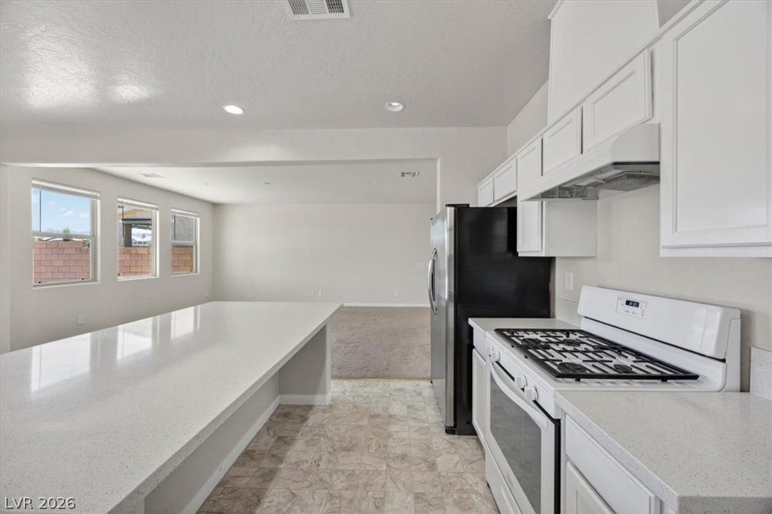 1116 Strada Cristallo, Henderson, NV 89011 A well-lit kitchen boasts ample counter space, a gas range, and a stainless steel refrigerator.