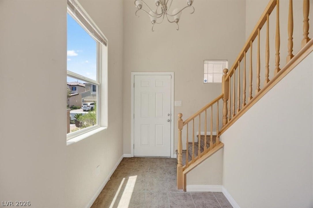 1116 Strada Cristallo, Henderson, NV 89011 A graceful staircase with wood banisters ascends from the tile entry, bathed in sunlight from a large window.