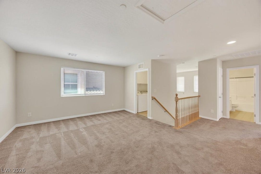 1116 Strada Cristallo, Henderson, NV 89011 A spacious, naturally illuminated room featuring warm neutral tones and comfortable carpeting.