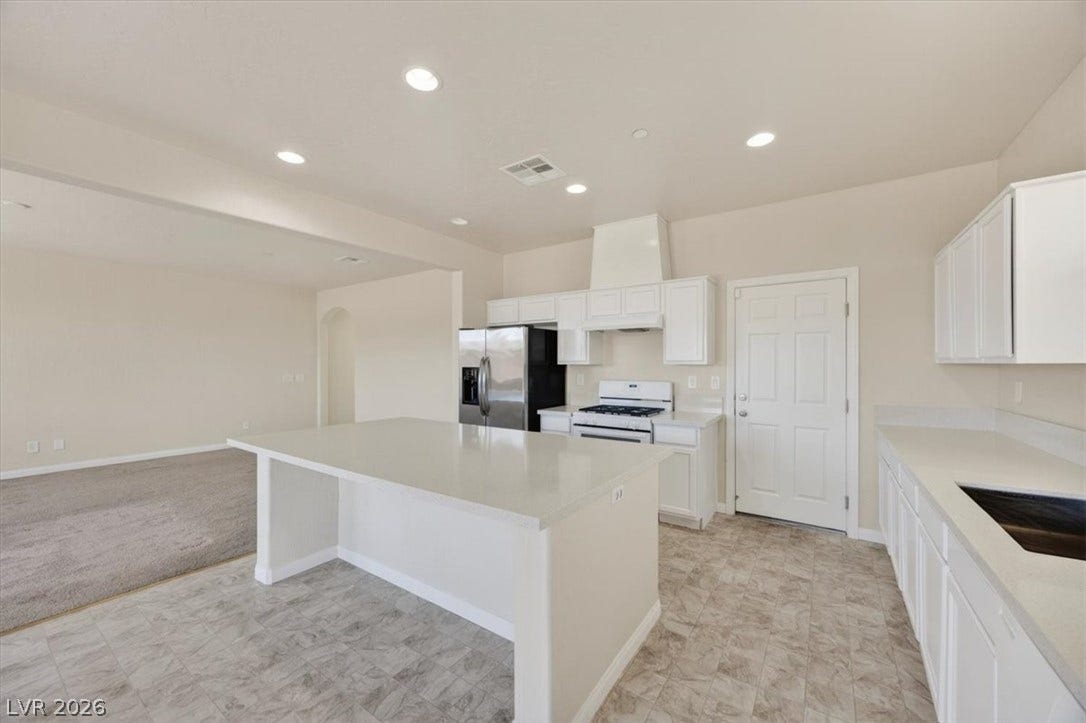 1116 Strada Cristallo, Henderson, NV 89011 A well-appointed kitchen showcasing an island and modern appliances, flowing into an adjacent living area.