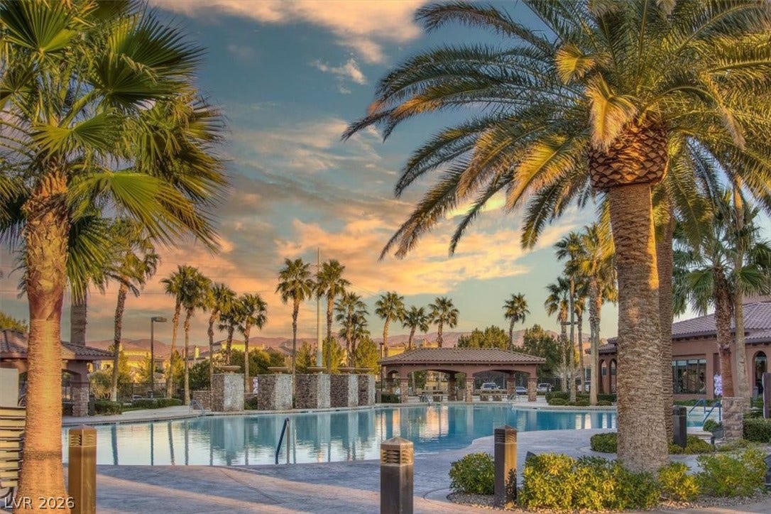 1116 Strada Cristallo, Henderson, NV 89011 Palm trees frame a sparkling pool under a vibrant sunset, highlighting the recreational amenities.