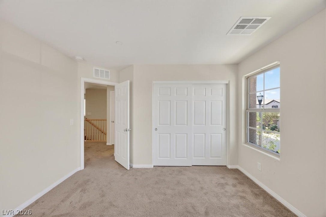 1116 Strada Cristallo, Henderson, NV 89011 A well-lit bedroom with fresh carpet and a bright window overlooking the neighborhood.