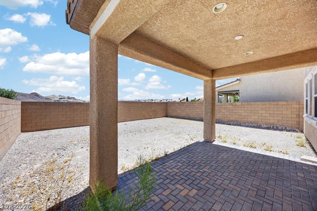 1116 Strada Cristallo, Henderson, NV 89011 A spacious covered patio with paver flooring awaits, overlooking the expansive yard and distant mountains.