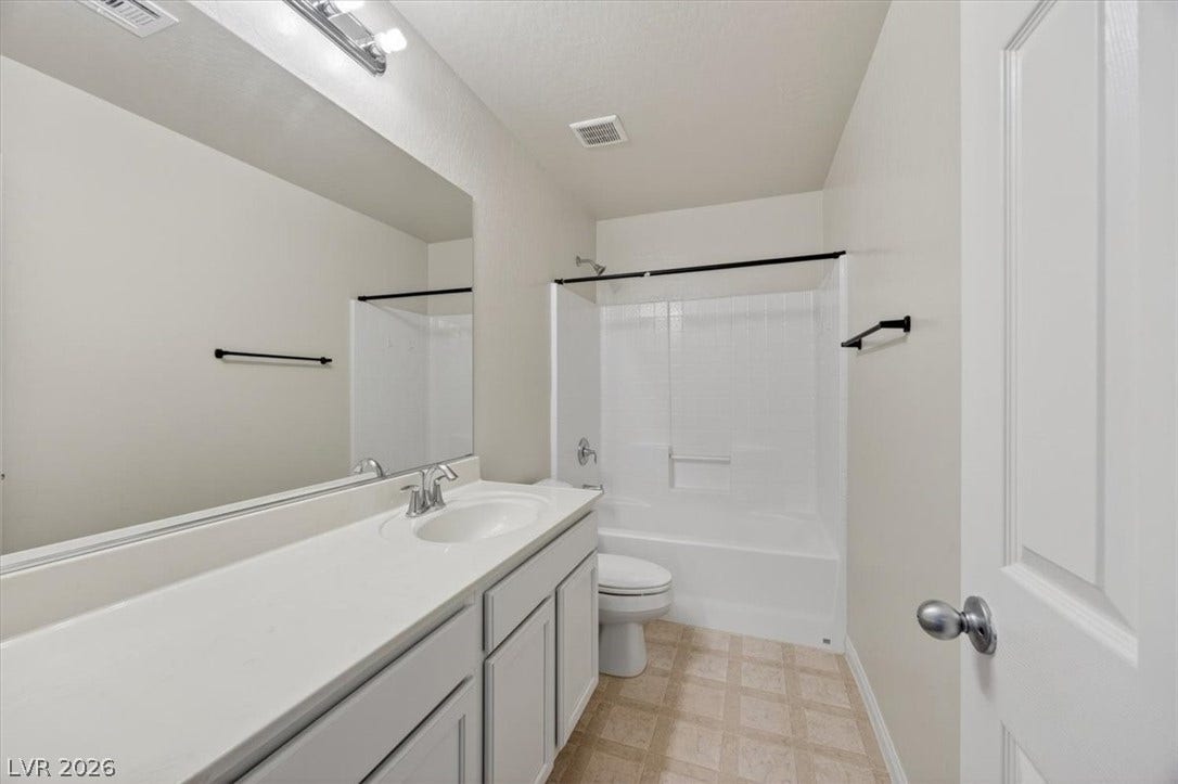 1116 Strada Cristallo, Henderson, NV 89011 A well-lit bathroom features a long vanity with an integrated sink and a full-sized mirror.