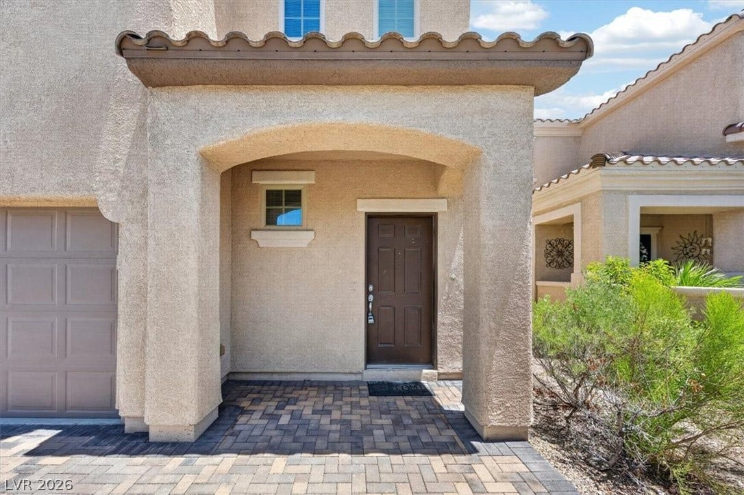 1116 Strada Cristallo, Henderson, NV 89011 A welcoming front entrance featuring textured stucco walls, a charming arched portico, and durable paver flooring.