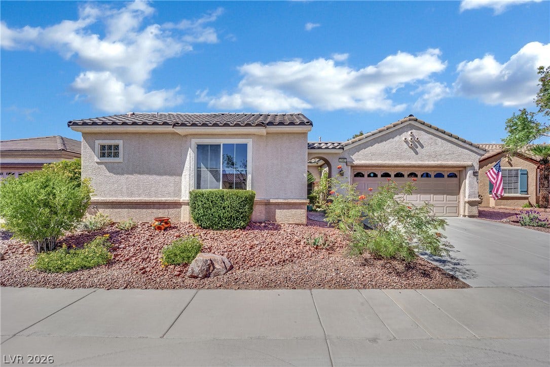 This desert-landscaped residence features a tile roof and an attached garage.