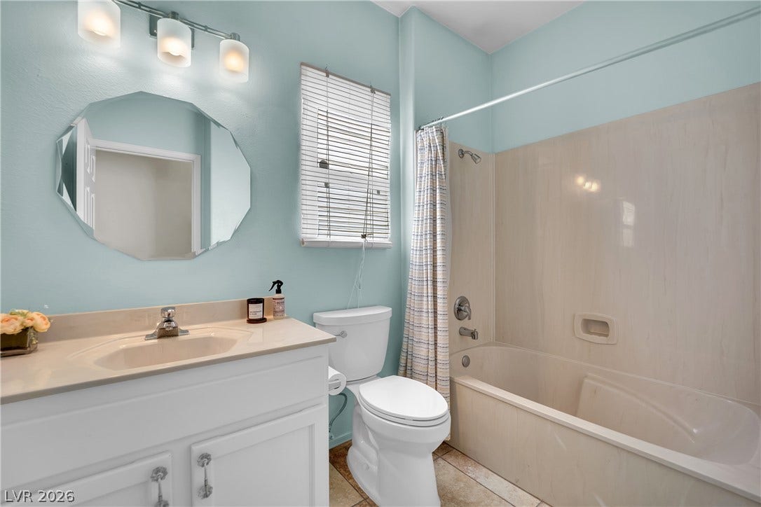 This bright bathroom features a single vanity, a toilet, and a bathtub with a shower.