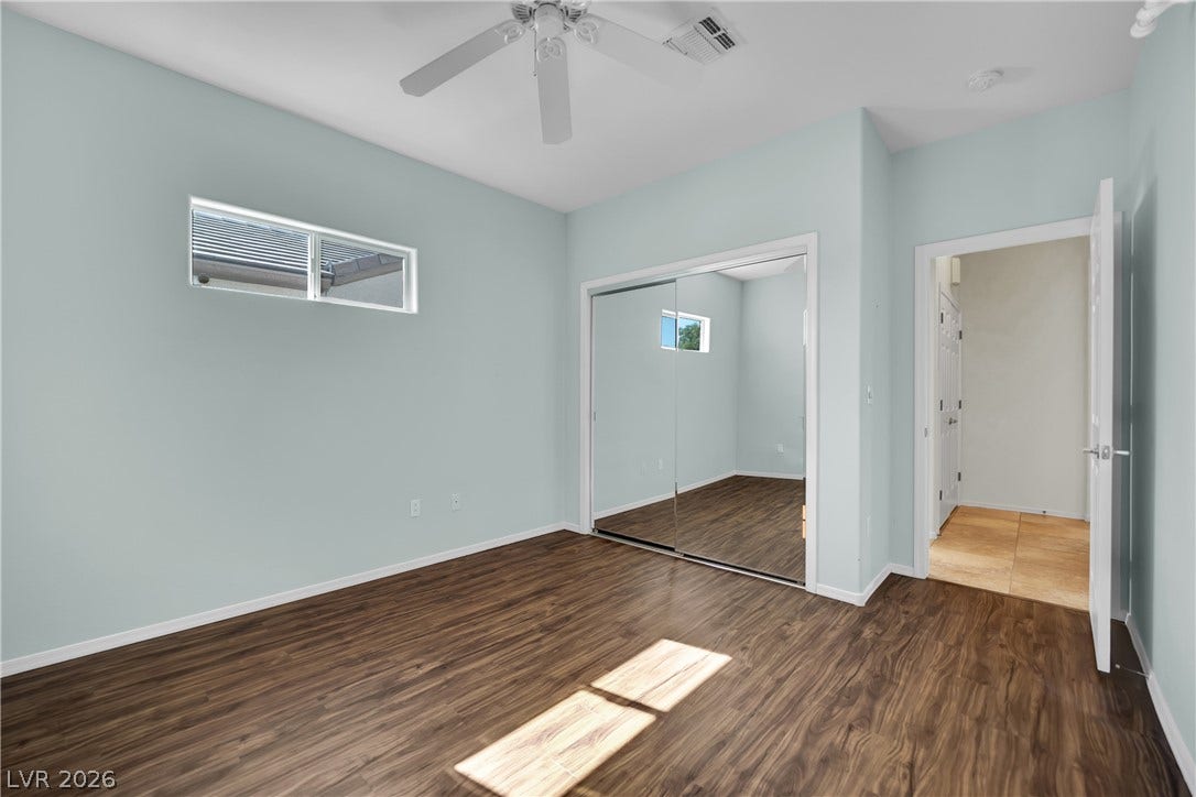 This bright room features a clean design with rich flooring and a mirrored closet.