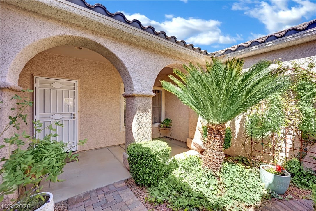 This charming entryway features inviting arches and lush, easy-care landscaping.