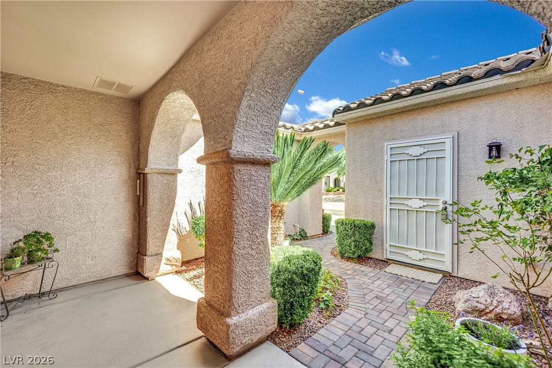 This inviting entrance features elegant arched pillars and a paved pathway leading to the front door.