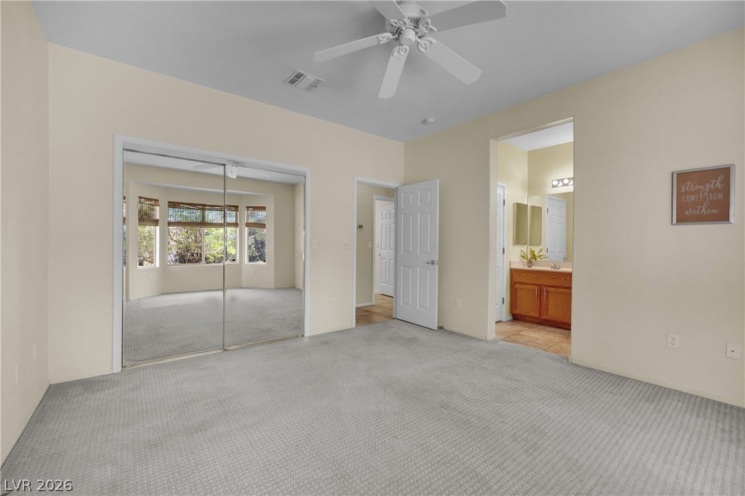 This spacious bedroom offers ample natural light and direct access to a private bathroom.