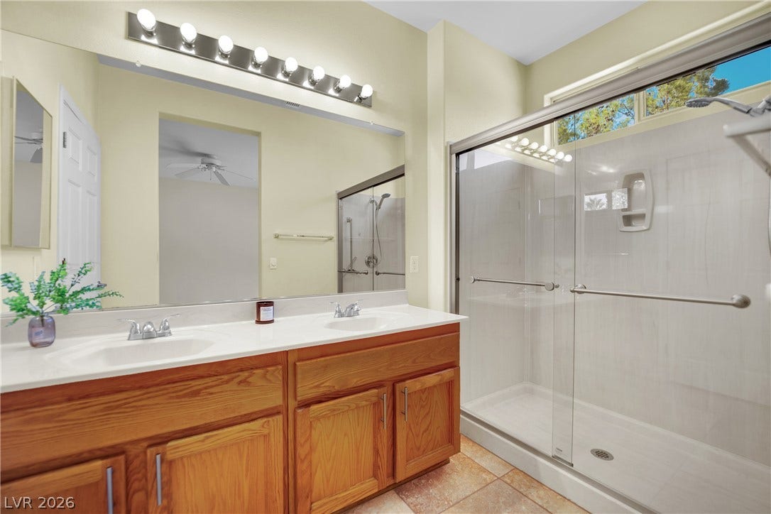 This bright bathroom features a spacious shower and a wide vanity with ample storage.