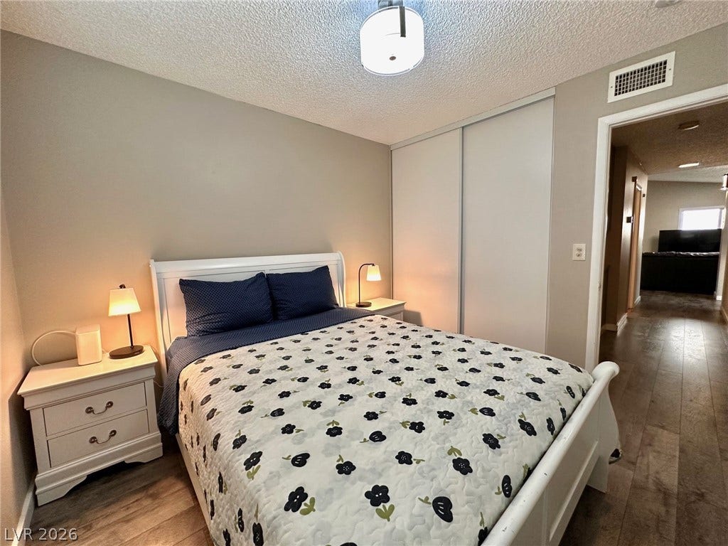 2340 Viewcrest Road, Henderson, NV 89014 This inviting bedroom features rich flooring and a spacious closet, offering comfort and convenience.