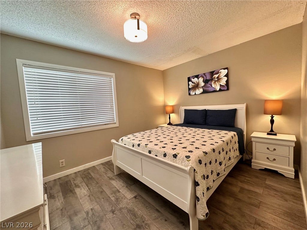 2340 Viewcrest Road, Henderson, NV 89014 This inviting bedroom features rich flooring and a large window for a peaceful retreat.