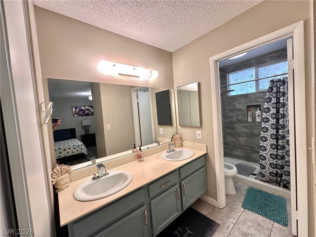 2340 Viewcrest Road, Henderson, NV 89014 This primary bathroom features a dual vanity, a spacious mirror, and an adjoining shower area.