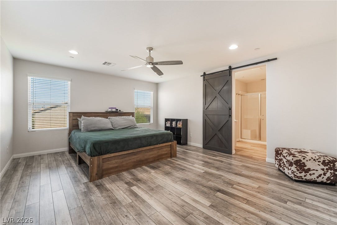 360 Misterioso Street, Henderson, NV 89011 This spacious room features ample natural light and a barn door leading to a primary bathroom.