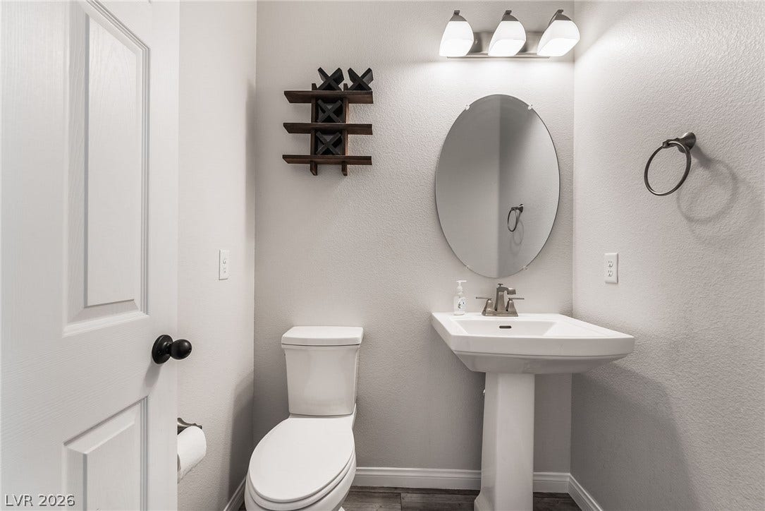 360 Misterioso Street, Henderson, NV 89011 This convenient bathroom features elegant wood flooring and a classic pedestal sink, offering functional design.