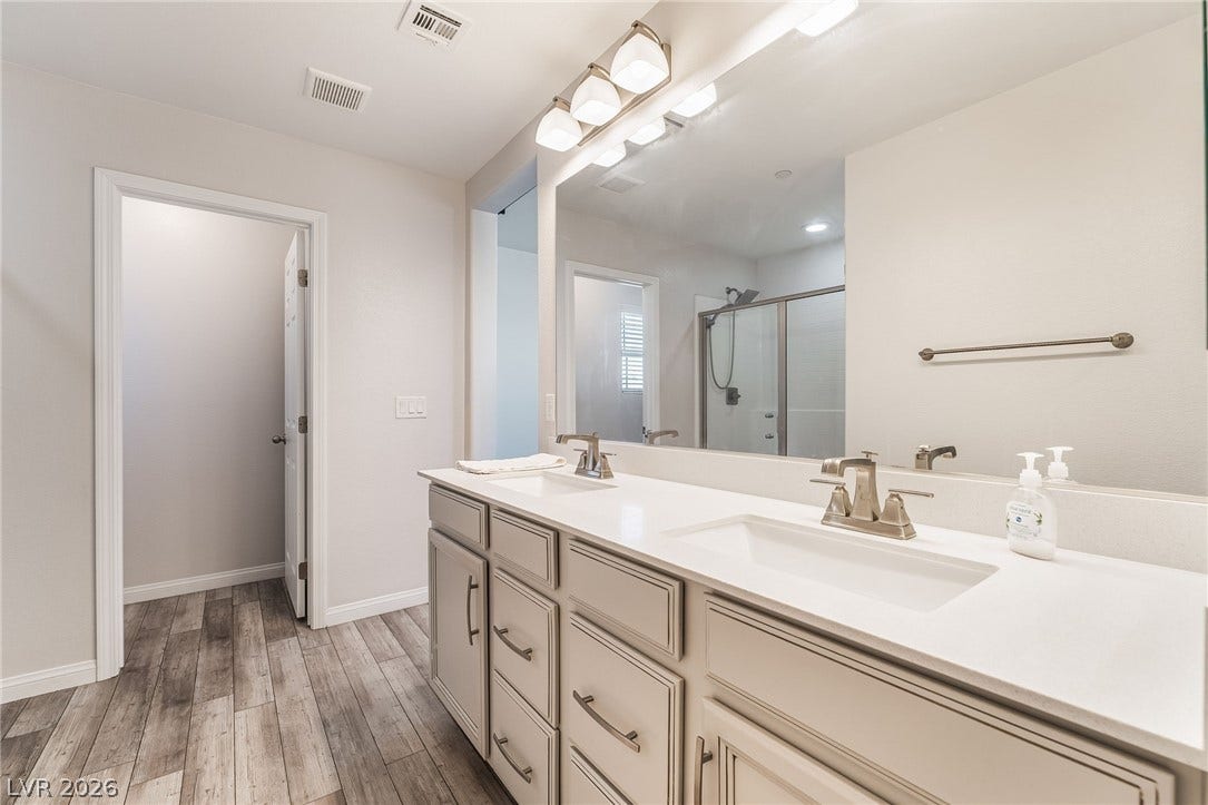 360 Misterioso Street, Henderson, NV 89011 This spacious bathroom features a double vanity and a glass-enclosed shower, offering comfort and style.