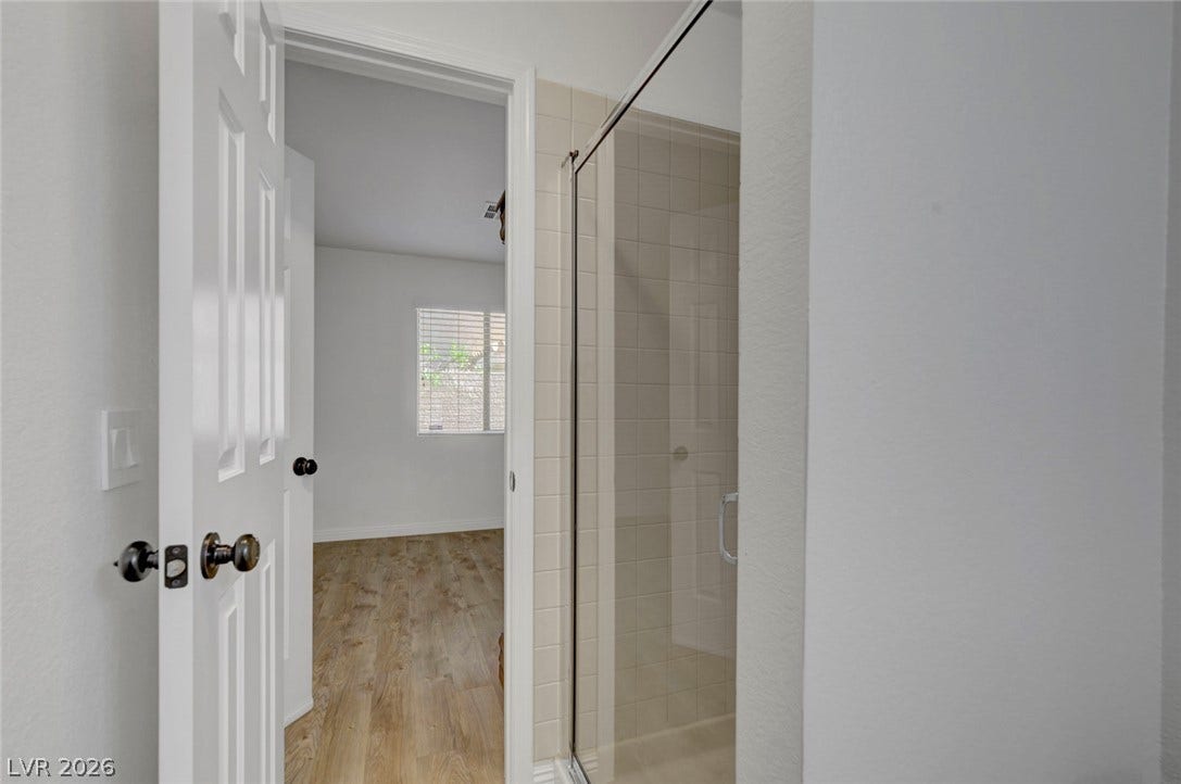 31 Antero Drive, Henderson, NV 89074 A well-appointed shower with glass enclosure offers convenience near a spacious bedroom with bright window light.
