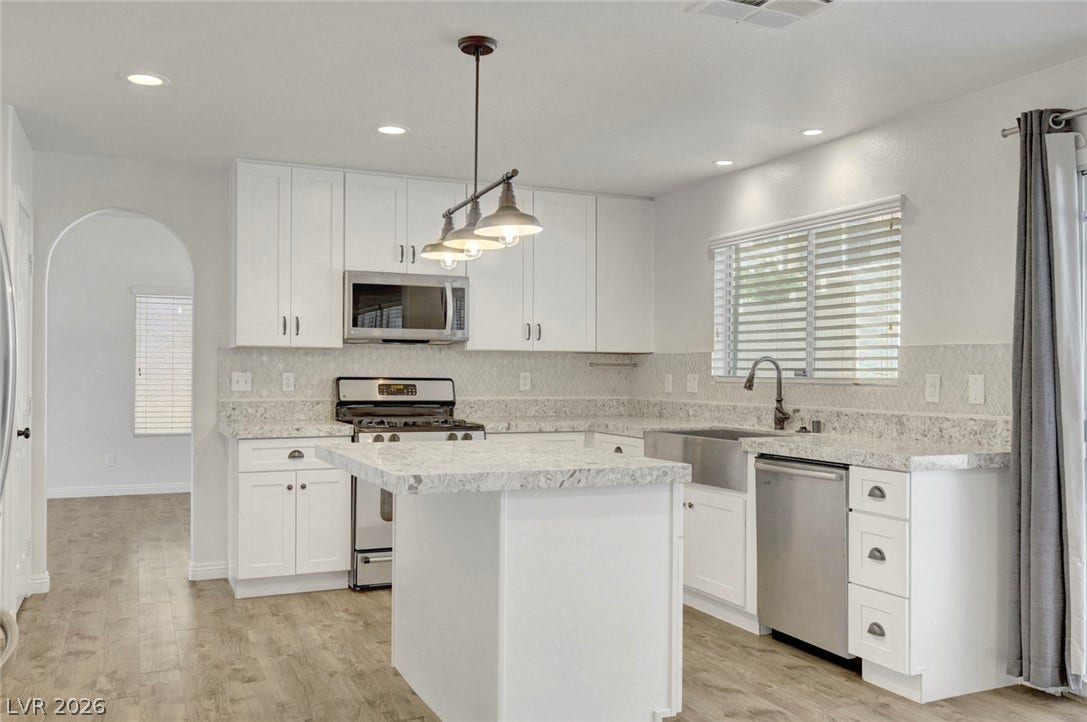 31 Antero Drive, Henderson, NV 89074 A well-lit kitchen with sleek white cabinetry, a central island, and modern stainless steel appliances.