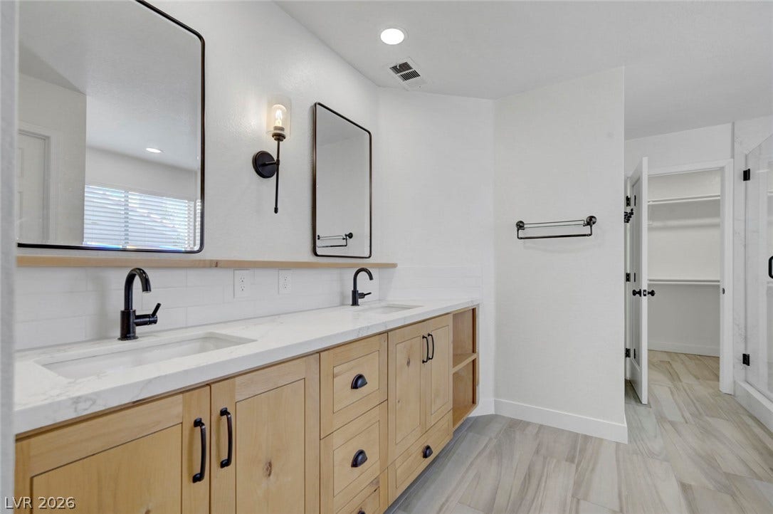 31 Antero Drive, Henderson, NV 89074 Dual vanity with sleek black fixtures and a spacious walk-in closet highlight this primary bathroom.